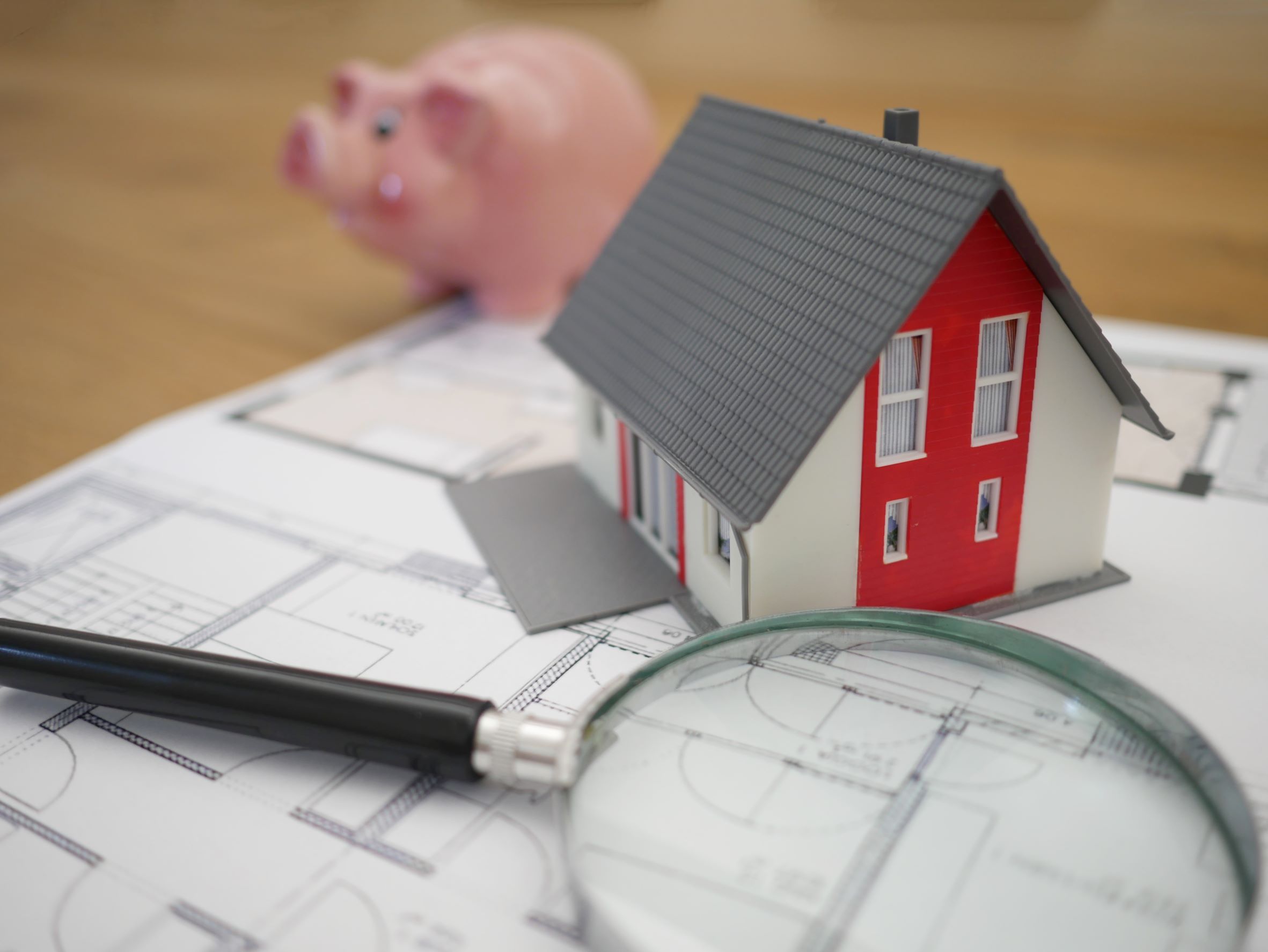 Image of a house, magnifying glass, floor plans, and coin bank. Photo by Tierra Mallorca on Unsplash