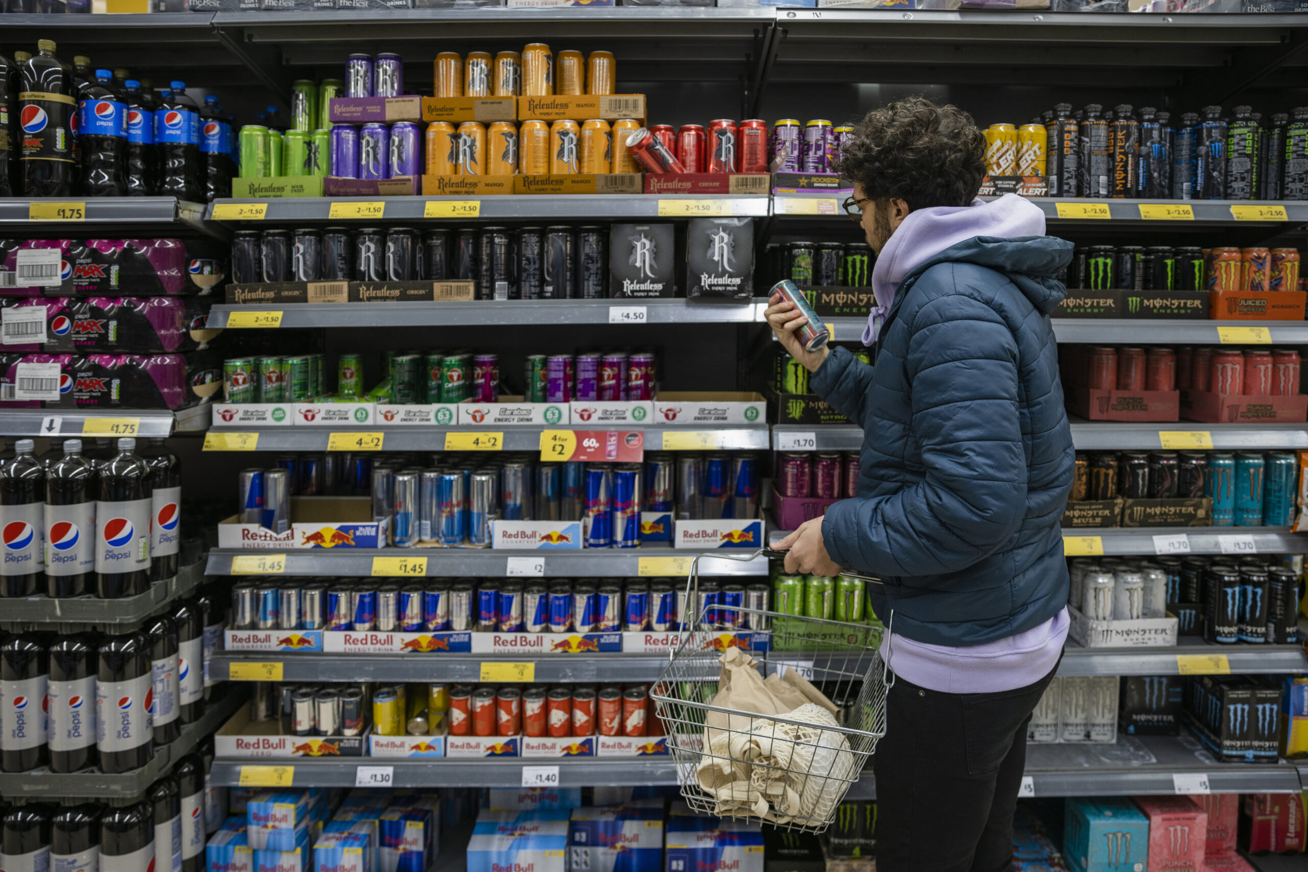 Man shopping in a supermarket while on a budget. He is looking for low prices due to inflation. He is living in the North East of England.